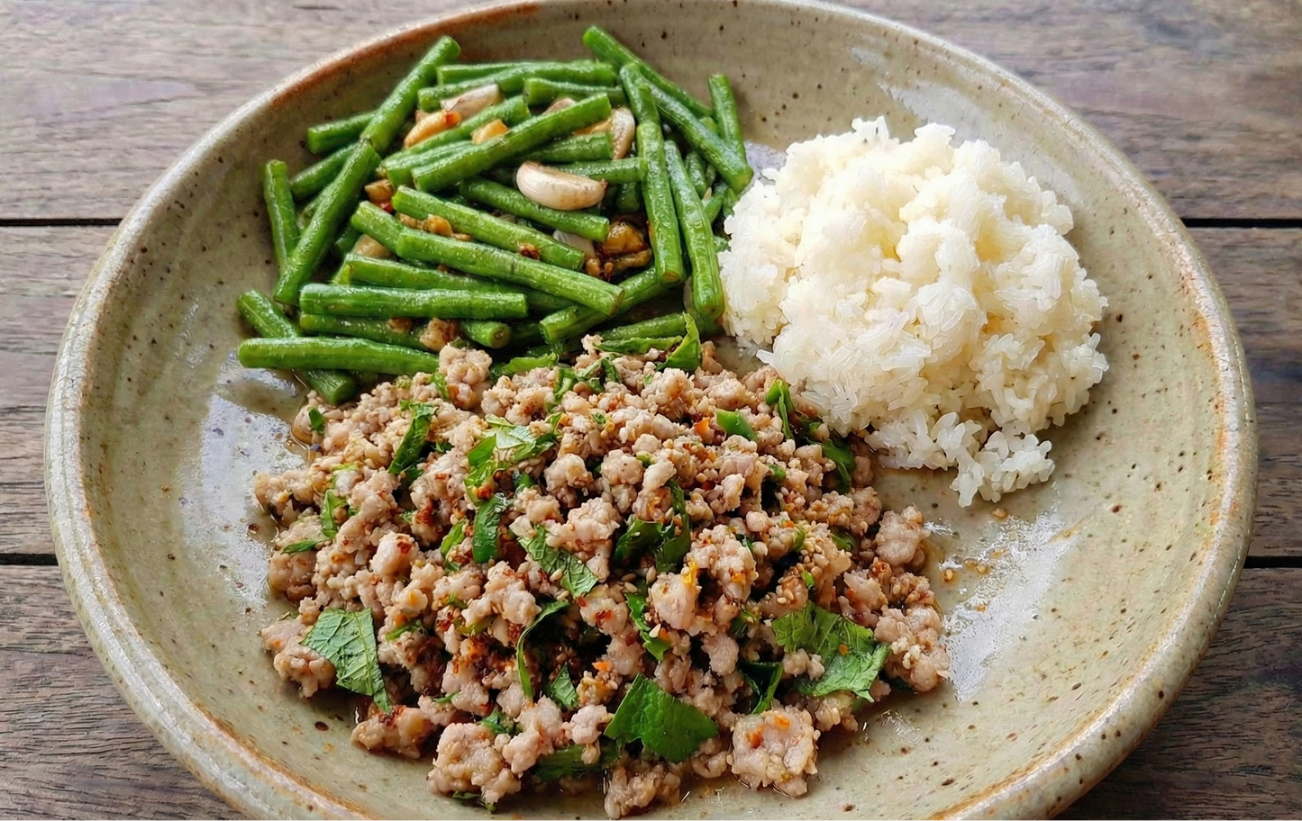 Plated dish with ground meat, green beans, and cauliflower rice on a wooden surface